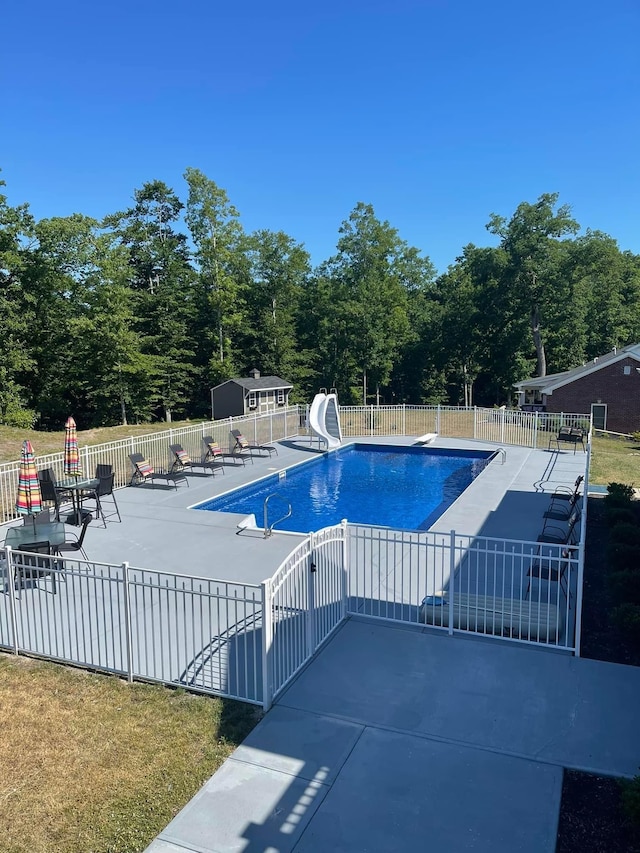 view of pool featuring a diving board, a patio area, and a water slide