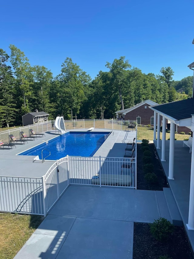 view of pool featuring a diving board, a patio area, and a water slide