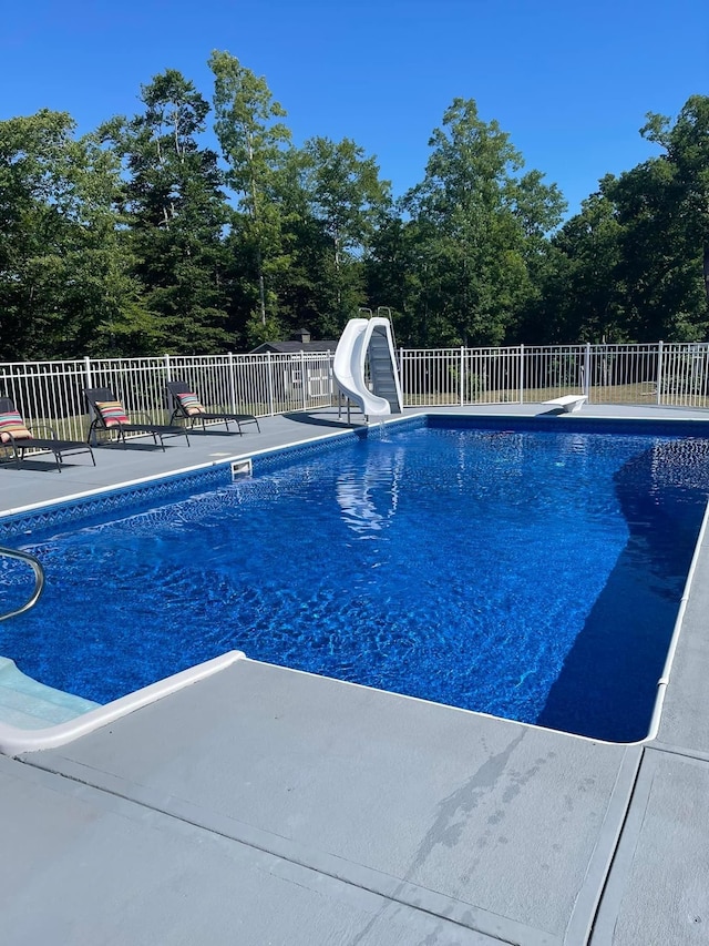 view of pool featuring a diving board, a patio, and a water slide