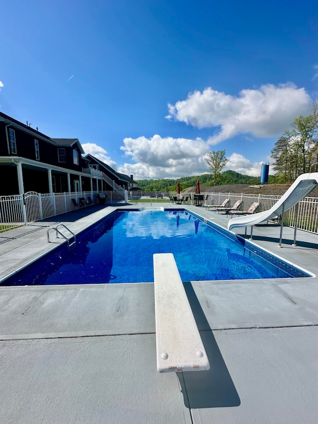 view of swimming pool featuring a patio area, a diving board, and a water slide