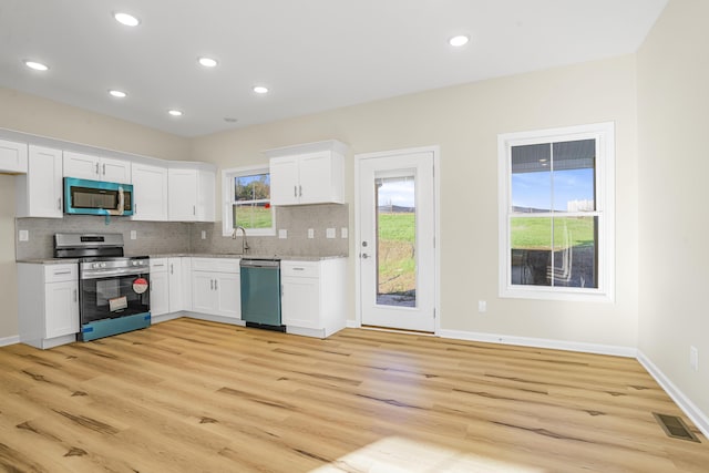 kitchen with appliances with stainless steel finishes, white cabinets, and backsplash