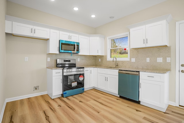 kitchen featuring sink, light hardwood / wood-style flooring, appliances with stainless steel finishes, tasteful backsplash, and white cabinets