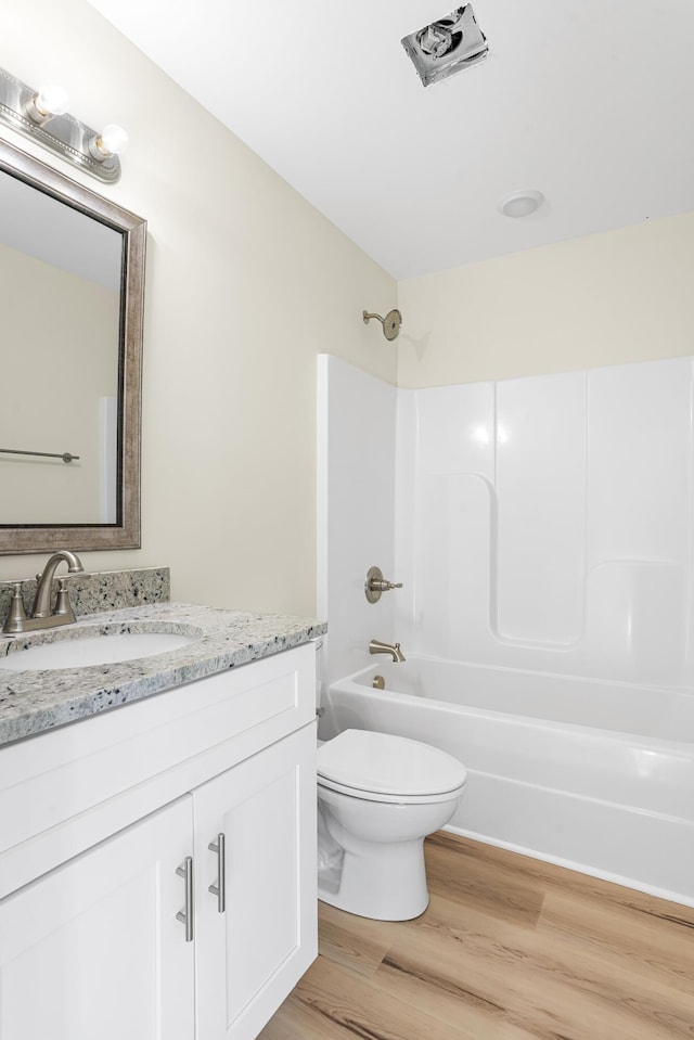 full bathroom with vanity, hardwood / wood-style flooring, shower / tub combination, and toilet