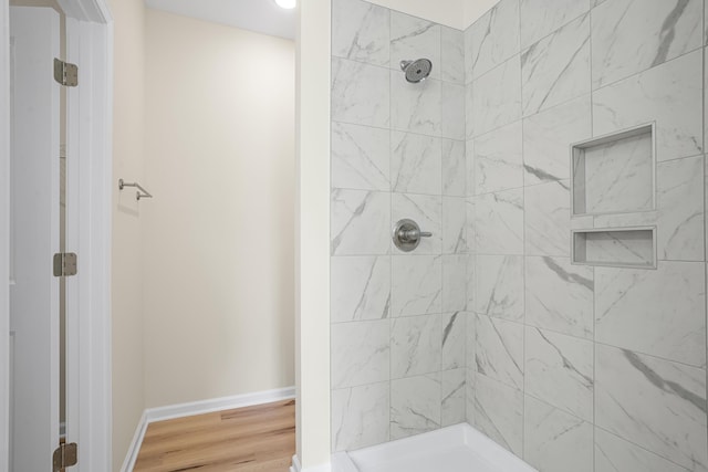 bathroom with wood-type flooring and tiled shower