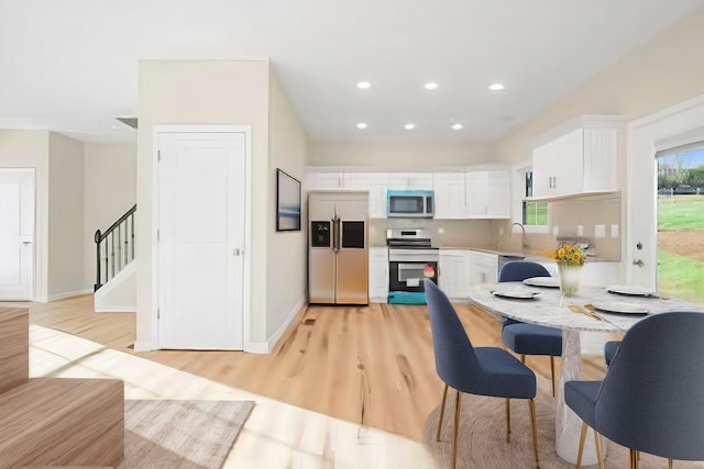 kitchen featuring stainless steel appliances, white cabinets, and light hardwood / wood-style flooring