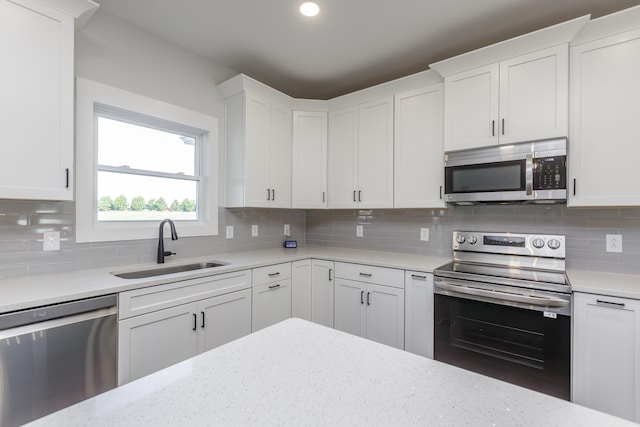 kitchen featuring decorative backsplash, white cabinets, and stainless steel appliances