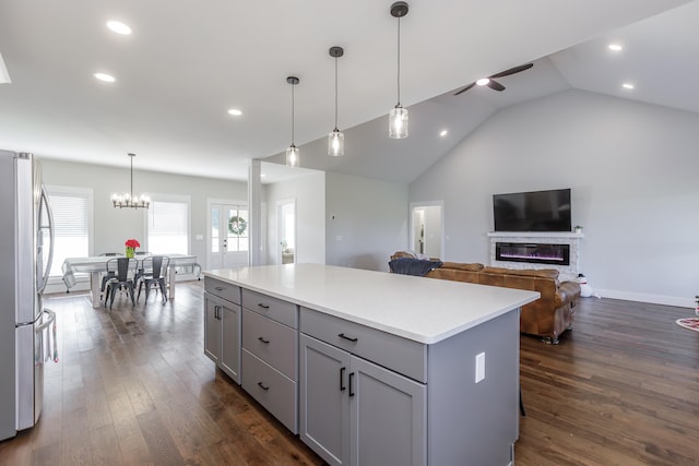 kitchen featuring gray cabinetry, dark wood-type flooring, a center island, stainless steel refrigerator, and lofted ceiling