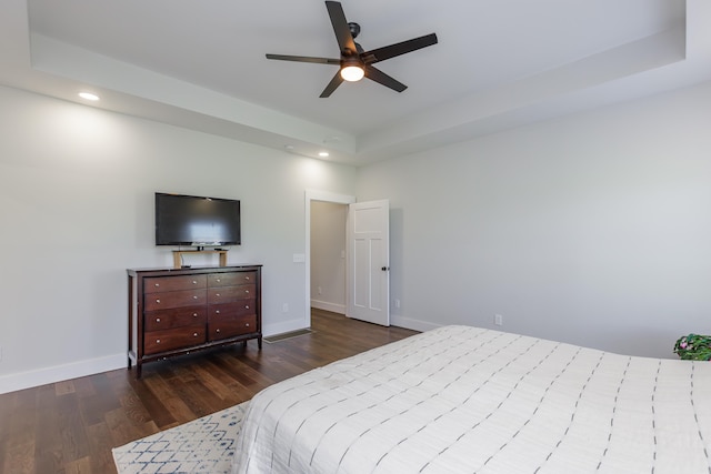 bedroom with a tray ceiling, ceiling fan, and dark hardwood / wood-style flooring