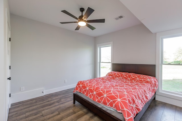 bedroom with ceiling fan, dark wood-type flooring, and multiple windows