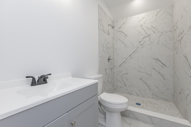 bathroom with a tile shower, vanity, and toilet