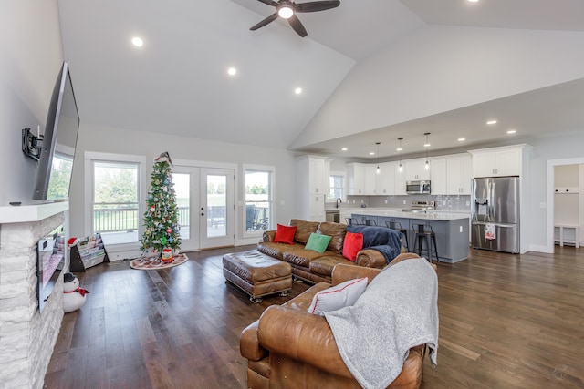 living room featuring a fireplace, high vaulted ceiling, ceiling fan, and dark wood-type flooring