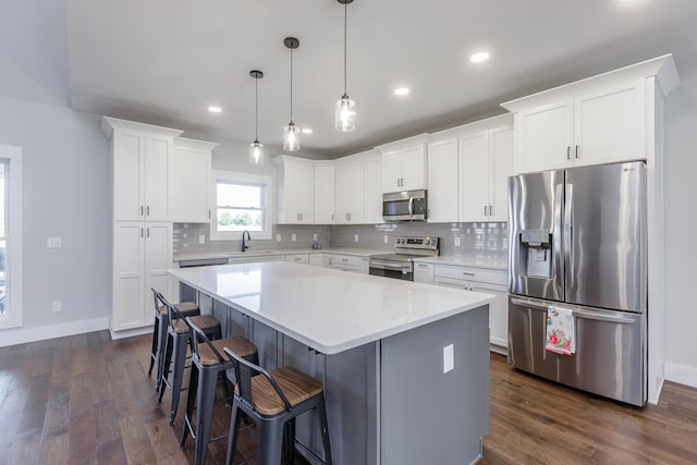 kitchen featuring pendant lighting, sink, appliances with stainless steel finishes, a kitchen island, and dark hardwood / wood-style flooring