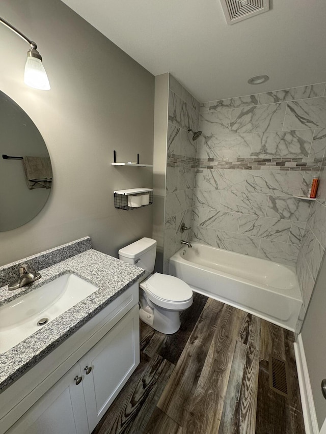 full bathroom featuring hardwood / wood-style flooring, vanity, toilet, and tiled shower / bath