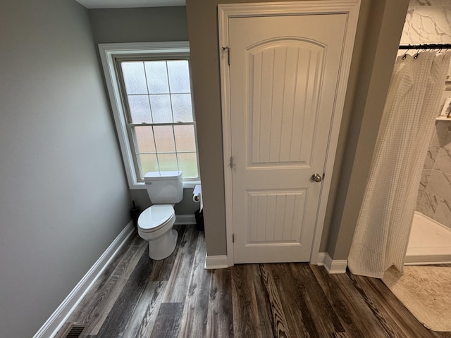 bathroom with hardwood / wood-style floors, toilet, and walk in shower