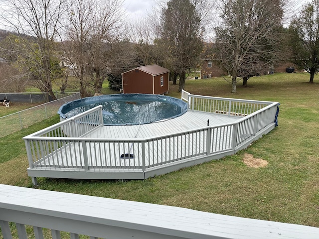 view of pool with a storage shed, a deck, and a yard