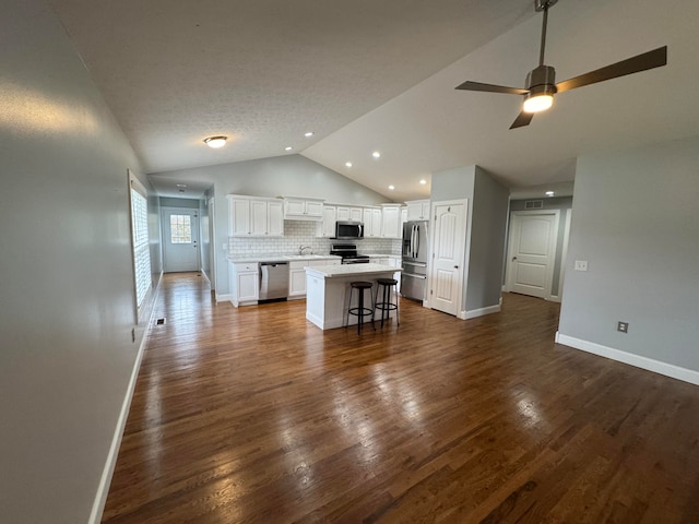 kitchen with a center island, a kitchen bar, white cabinets, dark hardwood / wood-style flooring, and stainless steel appliances