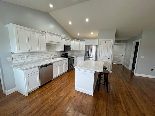 kitchen featuring a center island, dark hardwood / wood-style floors, appliances with stainless steel finishes, light stone counters, and white cabinetry