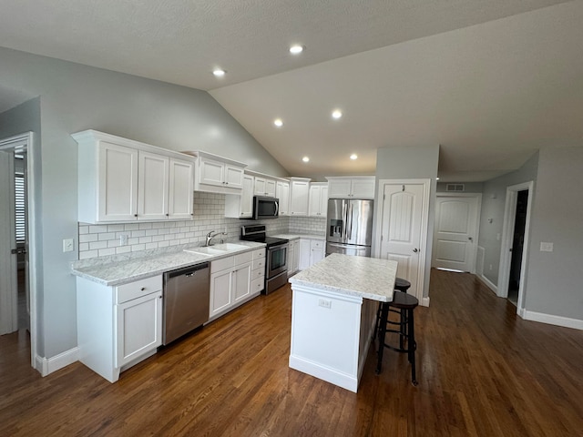 kitchen with white cabinetry, dark hardwood / wood-style flooring, a kitchen island, and appliances with stainless steel finishes