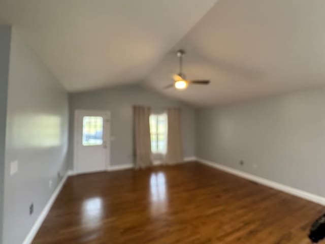 unfurnished living room featuring ceiling fan, dark hardwood / wood-style flooring, and vaulted ceiling