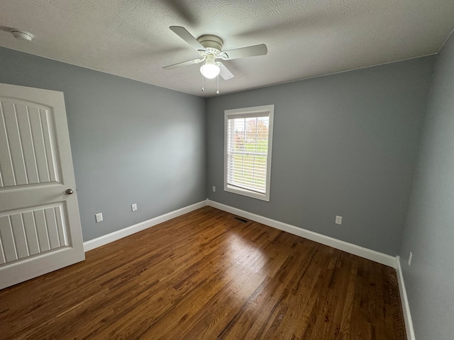 spare room with ceiling fan, dark wood-type flooring, and a textured ceiling