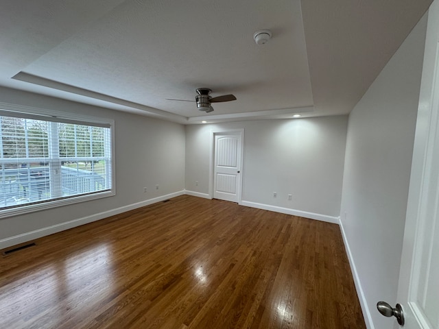 spare room featuring hardwood / wood-style floors, ceiling fan, and a raised ceiling