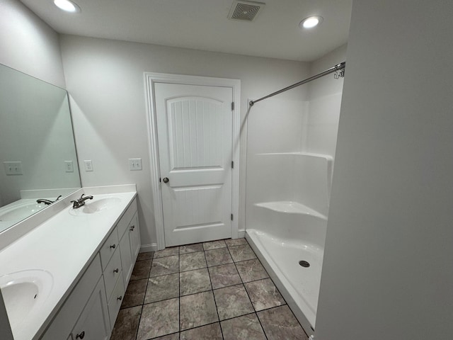 bathroom featuring tile patterned flooring, vanity, and walk in shower