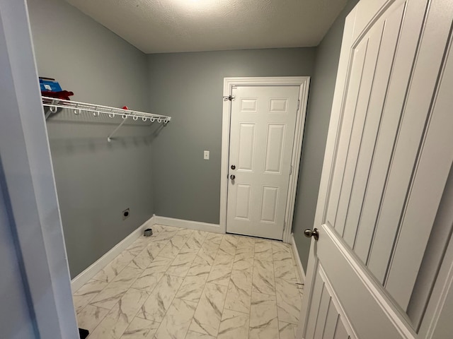 clothes washing area with hookup for an electric dryer and a textured ceiling