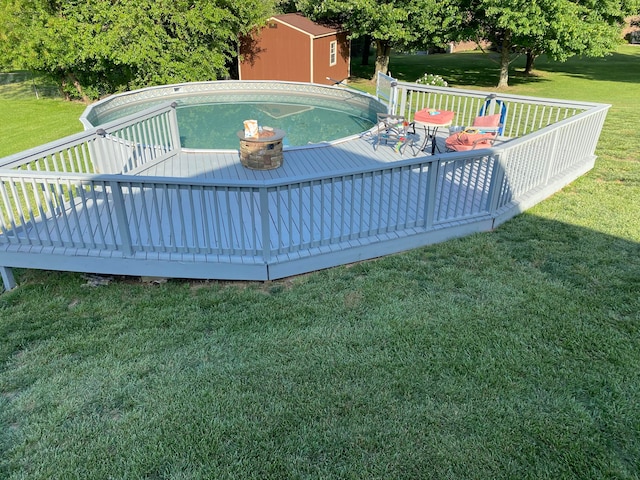 view of swimming pool featuring a yard, a shed, and a wooden deck