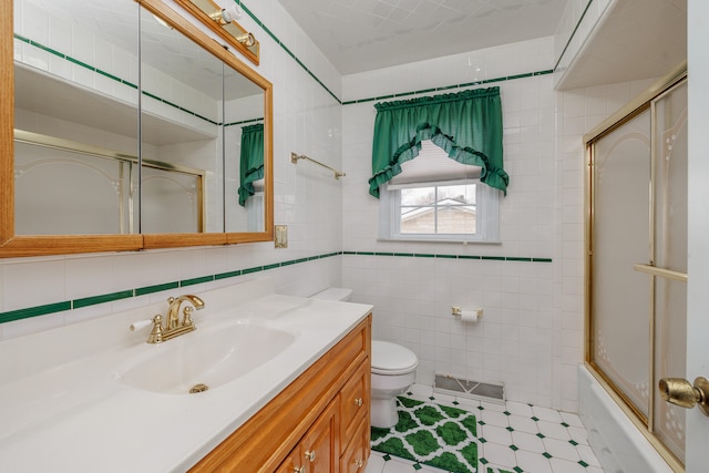 full bathroom with vanity, toilet, shower / bath combination with glass door, and tile walls