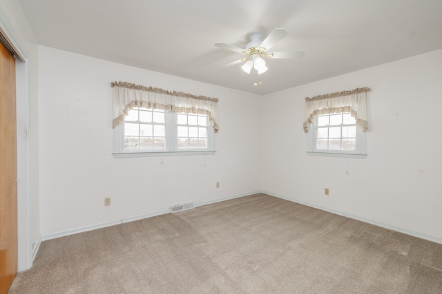 unfurnished bedroom with ceiling fan, a closet, light carpet, and multiple windows