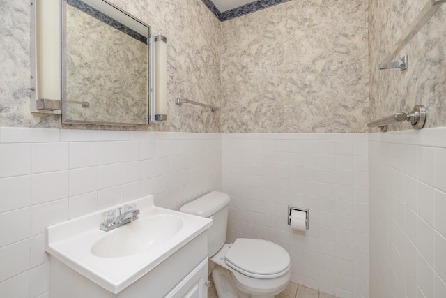 bathroom with vanity, toilet, and tile walls