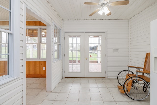 doorway featuring ceiling fan, wooden walls, and light tile patterned flooring