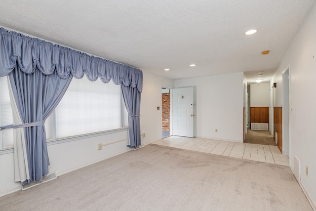 spare room featuring a textured ceiling and light colored carpet