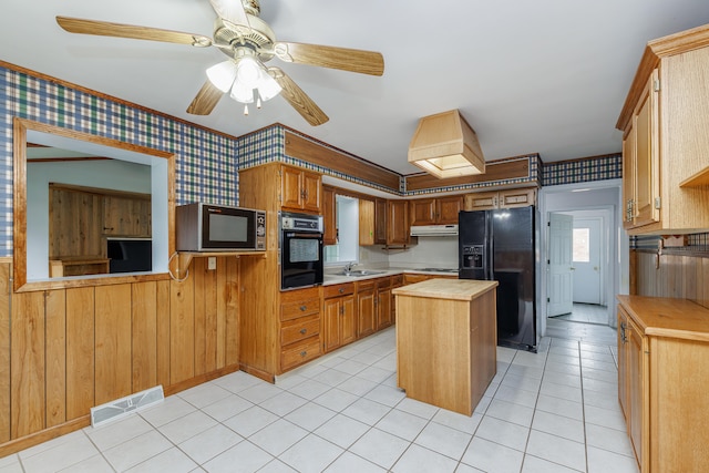 kitchen featuring wooden counters, ceiling fan, sink, black appliances, and a center island