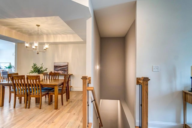 dining room with a raised ceiling, light wood-type flooring, and a chandelier