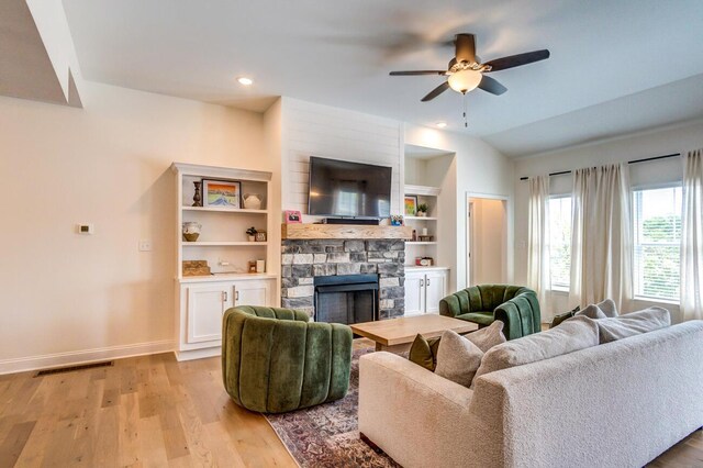 living room featuring lofted ceiling, ceiling fan, built in shelves, a fireplace, and light hardwood / wood-style floors