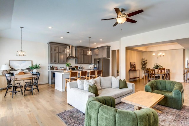 living room with ceiling fan with notable chandelier and light wood-type flooring