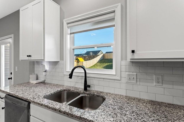 kitchen featuring white cabinets, light stone countertops, dishwasher, and sink