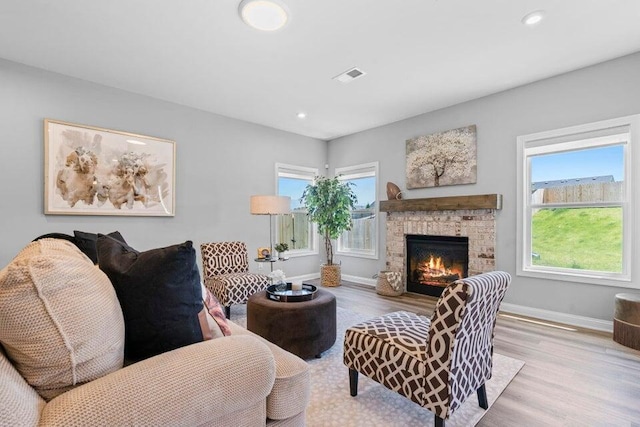 living room featuring light hardwood / wood-style flooring and a stone fireplace