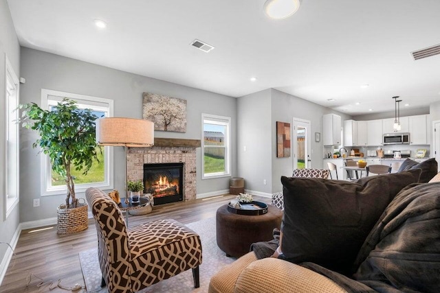 living room featuring plenty of natural light, dark hardwood / wood-style floors, and a brick fireplace