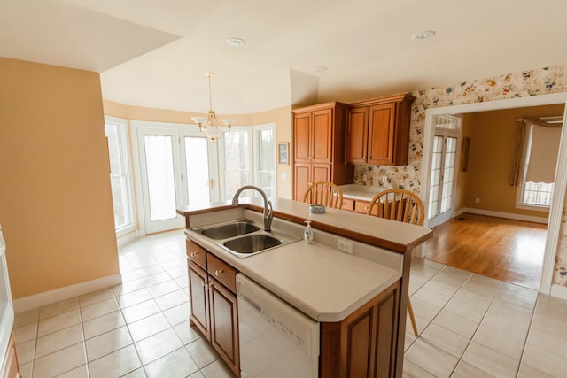 kitchen featuring dishwasher, a kitchen island with sink, sink, light hardwood / wood-style flooring, and a chandelier