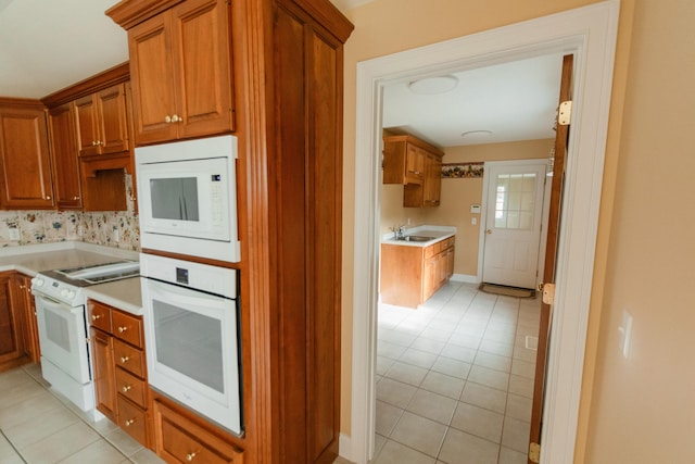 kitchen with sink, light tile patterned floors, and white appliances