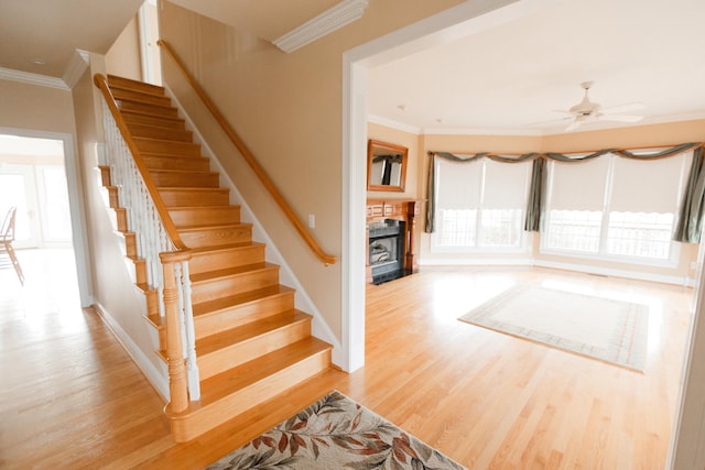 stairway with ceiling fan, ornamental molding, and hardwood / wood-style flooring