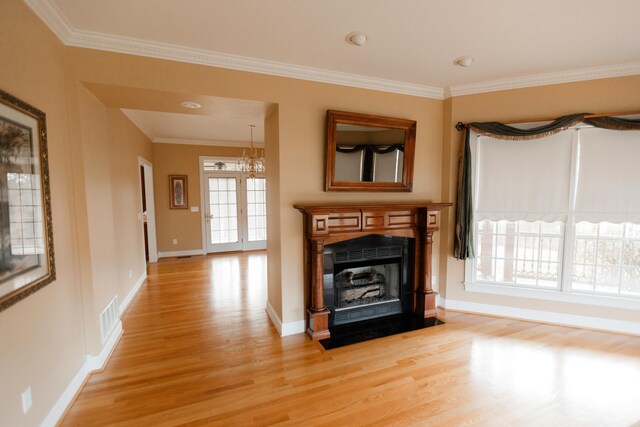 unfurnished living room with a chandelier, ornamental molding, and light wood-type flooring