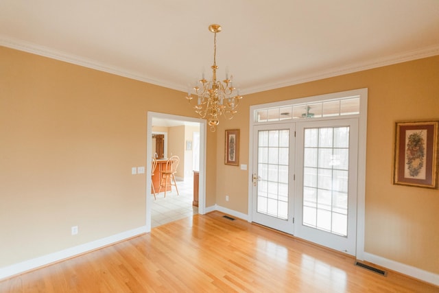 interior space featuring hardwood / wood-style floors, crown molding, and an inviting chandelier