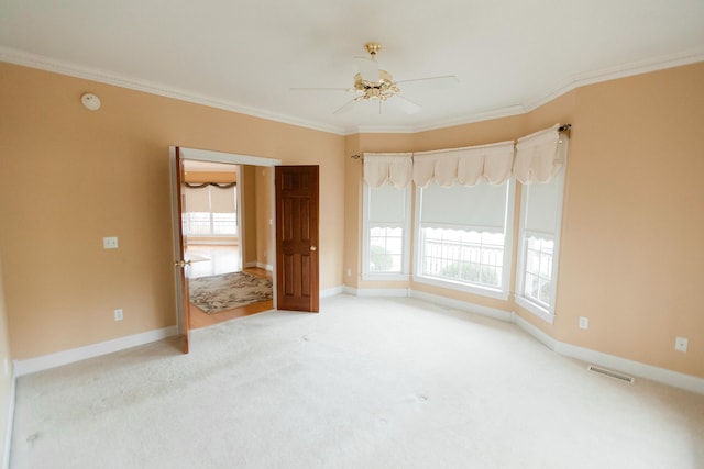 empty room featuring carpet flooring, crown molding, and ceiling fan