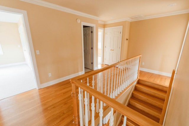 stairway with crown molding and wood-type flooring