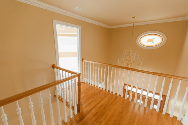 stairs with crown molding, hardwood / wood-style floors, and a notable chandelier