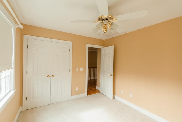 unfurnished bedroom featuring ceiling fan, light carpet, and a closet