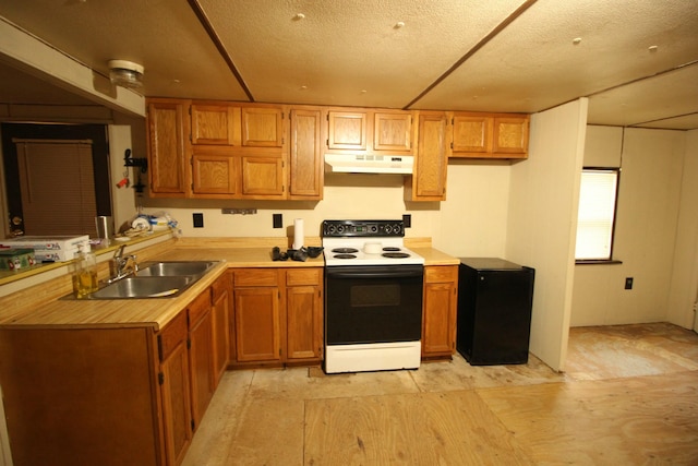 kitchen featuring black fridge, a textured ceiling, white range with electric cooktop, and sink